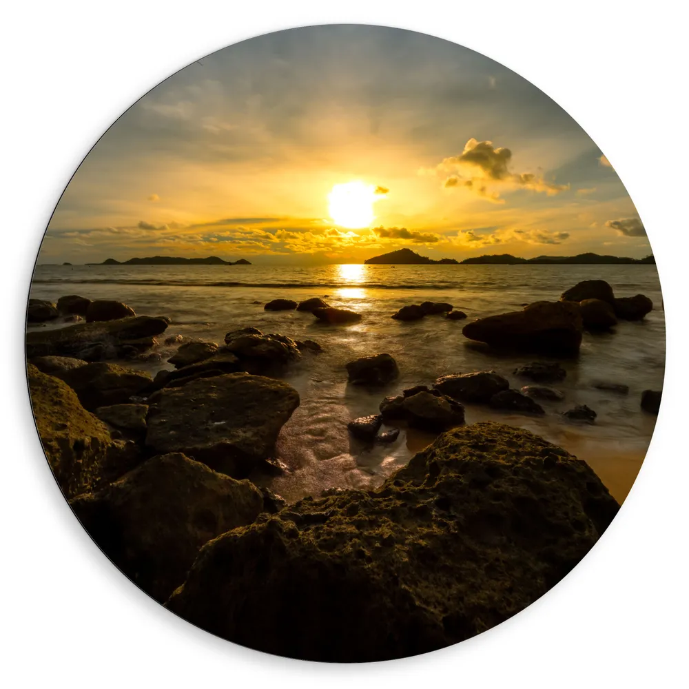 Dibond Muurcirkel - Zon verdwijnend achter Wolken boven de Zee vol Rotsen