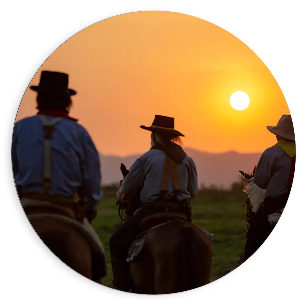 Dibond Muurcirkel - Achteraanzicht van Drie Cowboys op Paarden tijdens Felle Zonsondergang