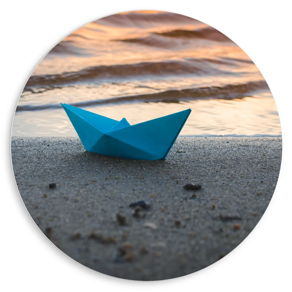Dibond Muurcirkel - Blauwe Papieren Origami Bootje Aangespoeld op het Strand tijdens Opkomende Zon