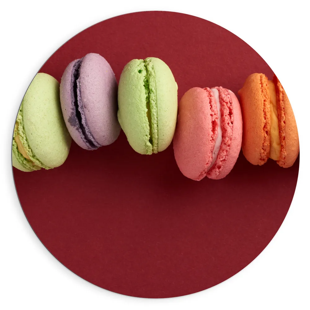 Dibond Muurcirkel - Rij van Verschillende Smaken Macarons op Rode Achtergrond