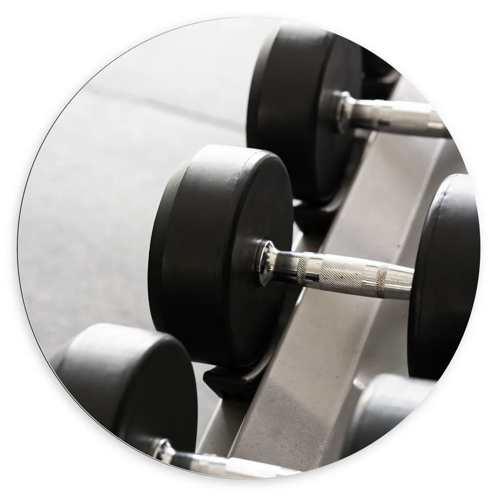 Dibond Muurcirkel - Foto van een Rij Dumbells (Zwart-wit)