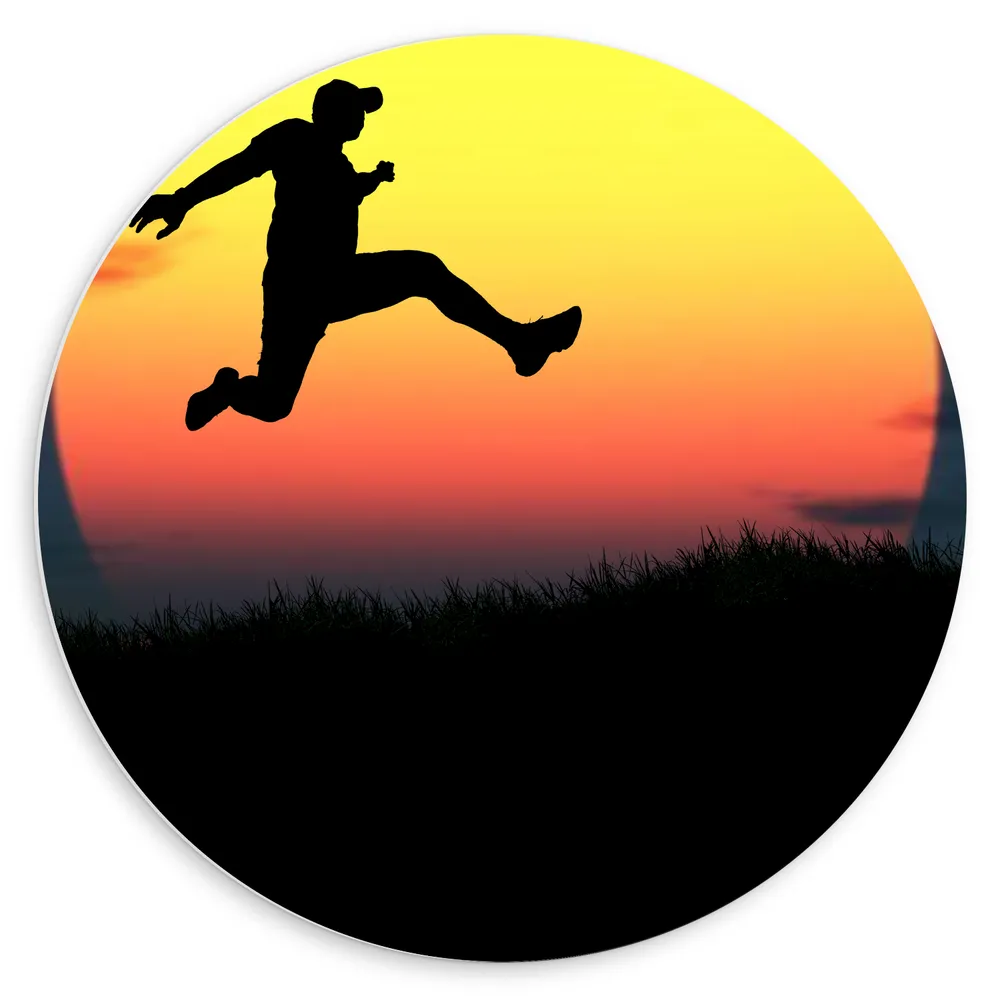 Dibond Muurcirkel - Silhouet van Springende Man in Grasveld voor de Horizon