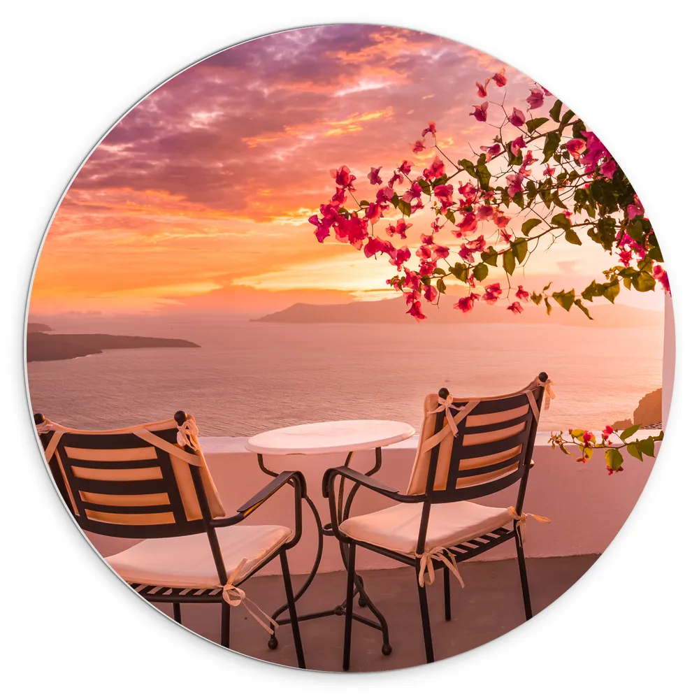 Dibond Muurcirkel - Tafel met Stoeljes op Balkon met Roze Bloemenstruik met Uitzicht op Zee