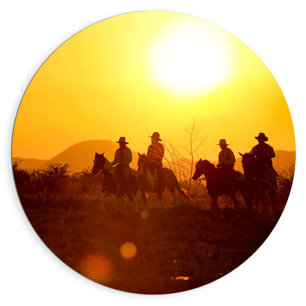 Dibond Muurcirkel - Groepje Cowboys op Paarden Rijdend door Landschap bij de Ondergaande Zon