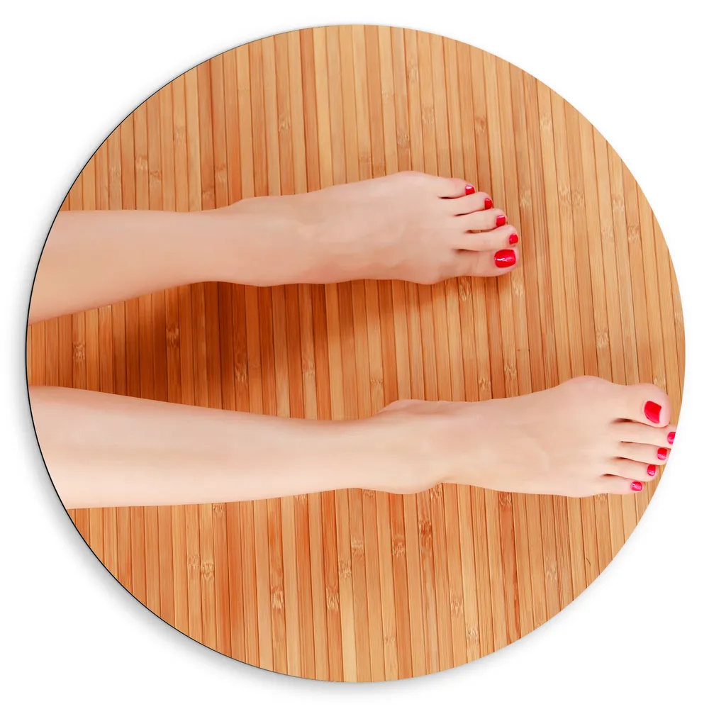 Dibond Muurcirkel - Bovenaanzicht van Vrouwen Benen met Roodkleurige Teennagels op Houten Ondergrond