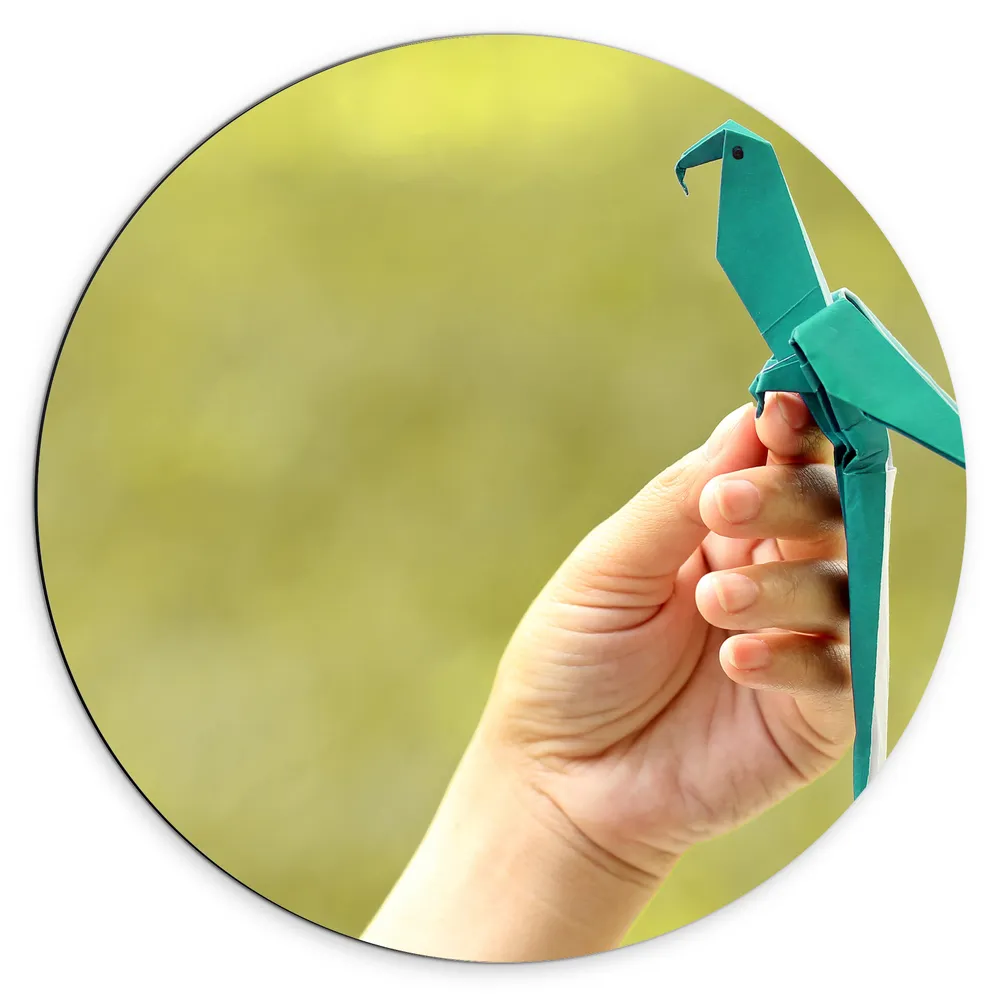Dibond Muurcirkel - Blauwe Origami Vogel op Hand van Mens in Groene Omgeving